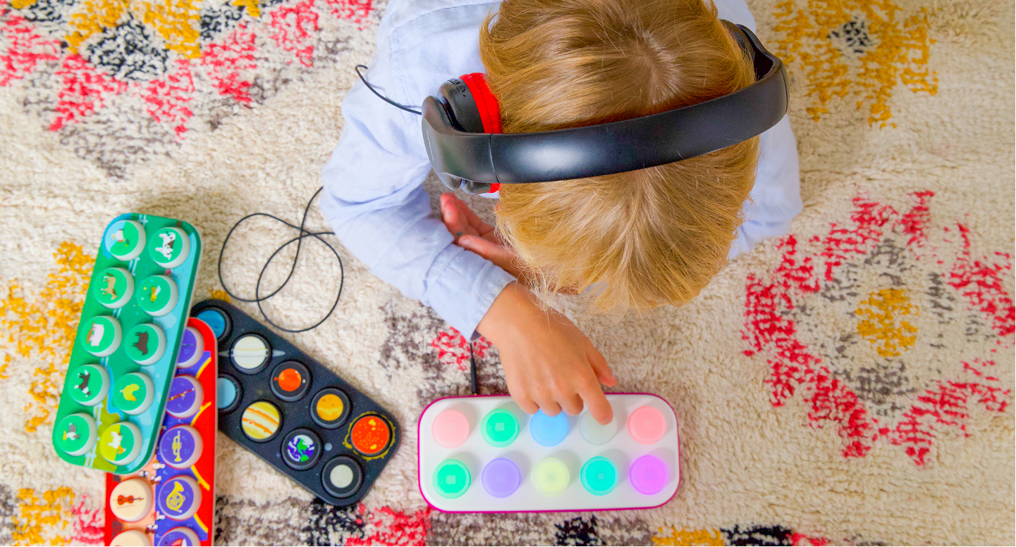 Child playing with colorful toys (Boppo and 3 Toppos) on a patterned rug