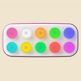 A rectangular device with rounded corners and a purple border, holding ten circular colored buttons arranged in two rows. The colors include pink, white, orange, green, blue, yellow, red, and purple, set against a solid light beige background.
