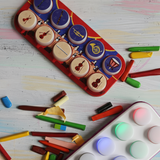Colorful children's musical instrument Toppo on a wooden surface with crayons and paint.