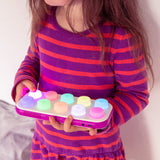 Young girl holding a colorful toy with a plain background