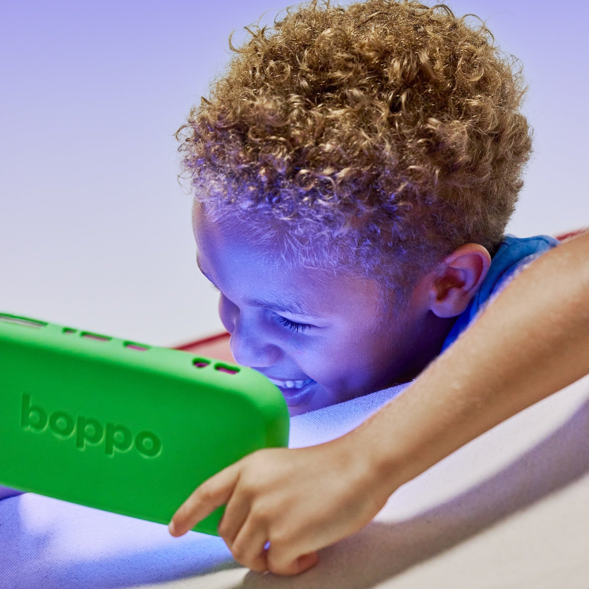 Child playing with a green electronic device labeled 'boppo' on a light purple background