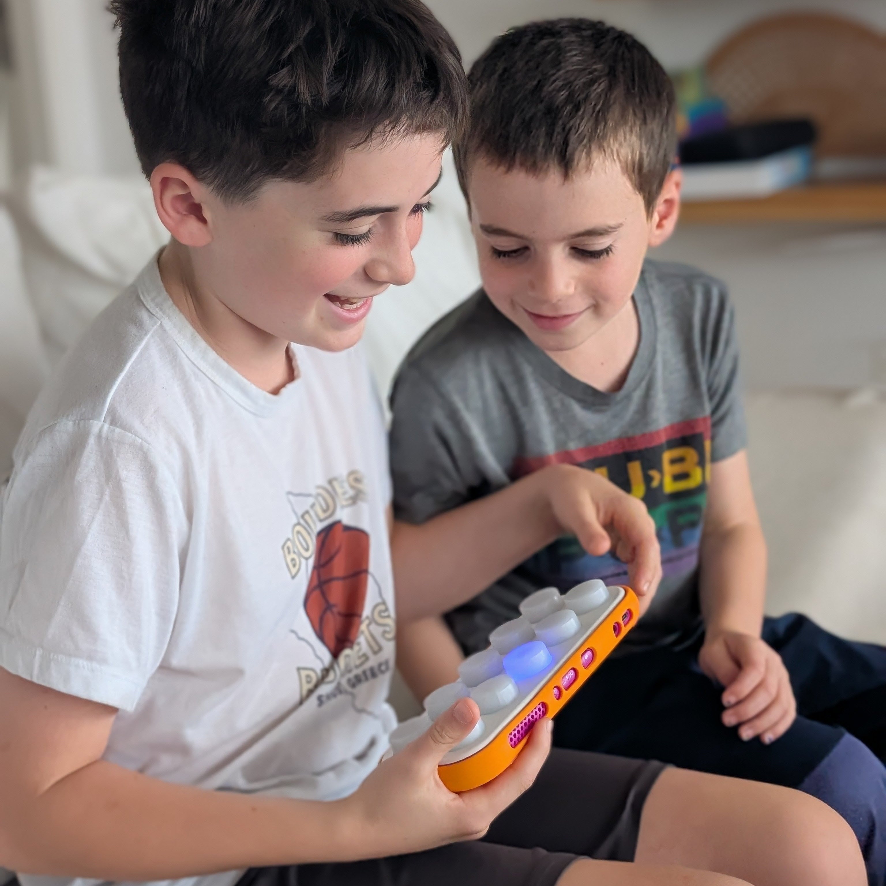 Two children playing with electronic devices on a couch.